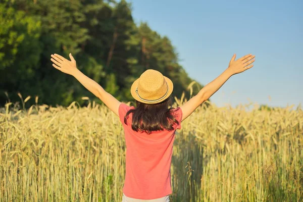 Meisje in hoed in tarwe veld met haar rug met open handen — Stockfoto