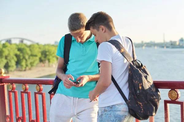 Två vänner tonårspojkar med smartphone, pratar och ler — Stockfoto