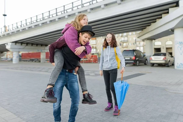 Мальчик-подросток и две девочки разговаривают и веселятся на открытом воздухе — стоковое фото
