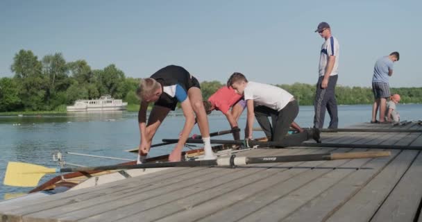 Kyjev UA, 31-07-2019. Sportovní tým dospívajících chlapců vedený trenérem, který spustil lodní kajaku do vody — Stock video