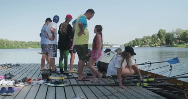 Kiev UA, 31-07-2019. Sport team van tiener meisjes geleid door bus verlagende boot kajak in het water — Stockvideo