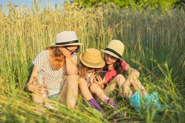 Retrato de tres niñas sentadas y descansando en la hierba — Foto de Stock