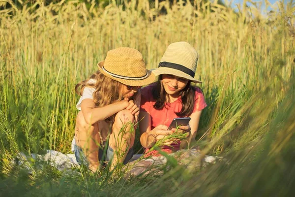 Летний портрет двух девушек, сидящих в траве — стоковое фото