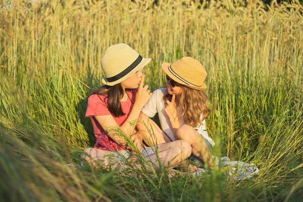 Two smiling girls sitting in grass, children talking — Stock Photo, Image