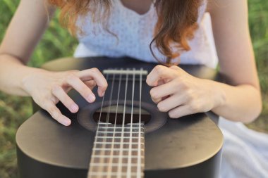 Gitar çalan kızın yakın elleri parmakları