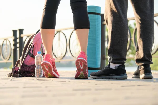 Primer plano de un par de piernas en zapatillas de deporte con botella de agua de la esterilla de ejercicio — Foto de Stock