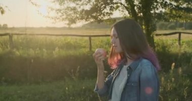 Genç güzel kız yürüyüş ve kırmızı elma yeme