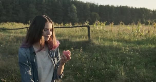 Joven hermosa chica caminando y comiendo manzana roja — Vídeos de Stock