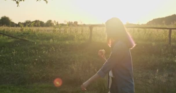 Joven chica feliz caminando y comiendo manzana roja — Vídeo de stock