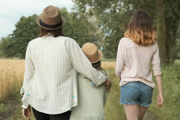 Mor och två döttrar går tillsammans längs landsväg, back View — Stockfoto