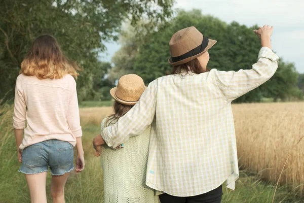 Matka a dvě dcery, které spolu chodí po venkovské silnici, pohled zpět — Stock fotografie