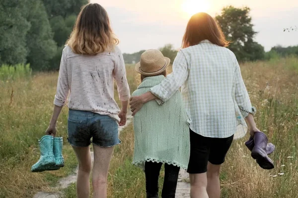 Мать и две дочери идут вместе по проселочной дороге — стоковое фото