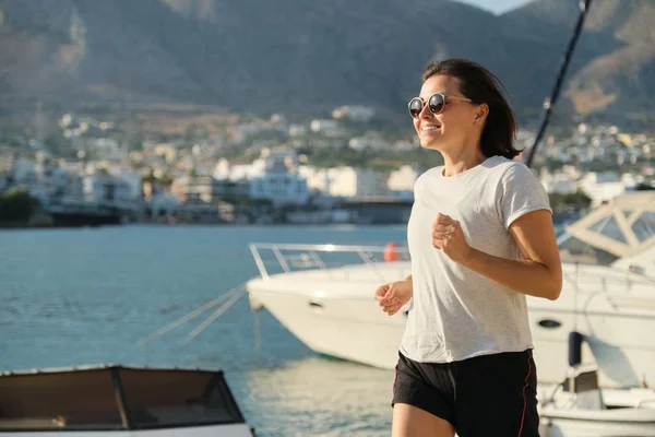 Glimlachende rijpe vrouw Running joggen op de promenade aan zee — Stockfoto