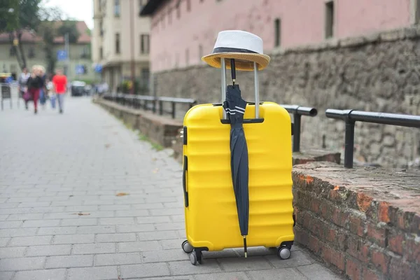 Reisetourismus-Konzept, gelber Plastikkoffer, Hut, Regenschirm — Stockfoto