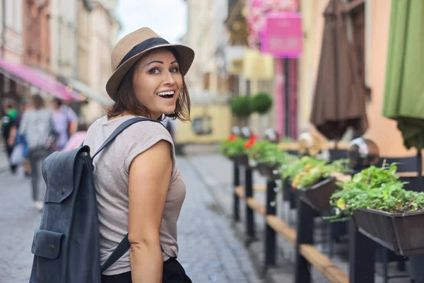 Mulher sorridente de meia idade em chapéu viajando na cidade turística — Fotografia de Stock