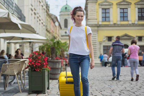 Menina viajante andando com mochila e mala amarela — Fotografia de Stock