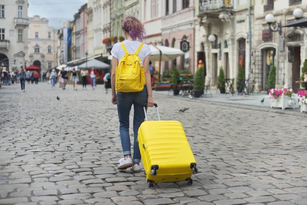 Мандрівник дівчина ходить з рюкзаком і жовтою валізою — стокове фото