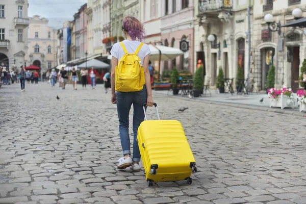 Chica viajero caminando con mochila y maleta amarilla — Foto de Stock