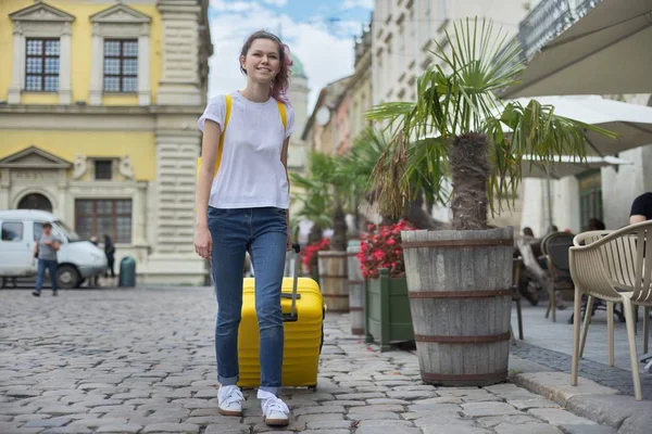 Menina viajante andando com mochila e mala amarela — Fotografia de Stock