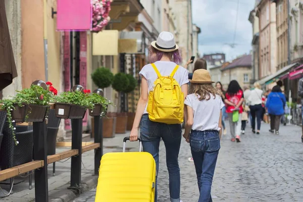 Twee meisjes wandelen in de stad met koffer, achteraanzicht — Stockfoto