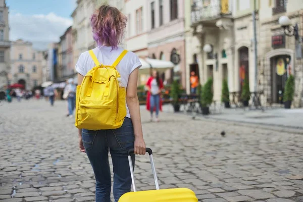 Menina viajante andando com mochila e mala, vista traseira . — Fotografia de Stock