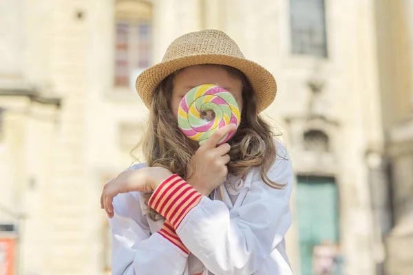 Urban outdoor portrait child girl with colorful lollipop — Stock Photo, Image