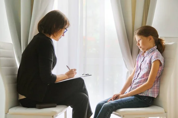 Woman elementary school teacher testing talking to girl