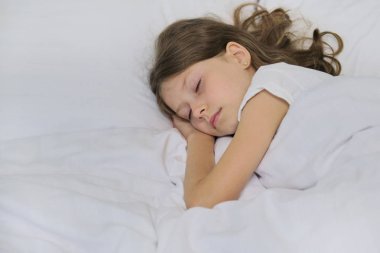 Yastıkta uyuyan kız çocuğu, beyaz yatak, yakın çekim yüzü.