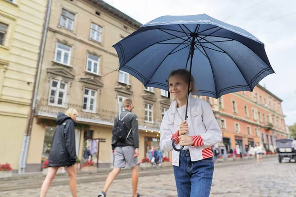 Маленькая девочка ходит с зонтиком на городской улице — стоковое фото