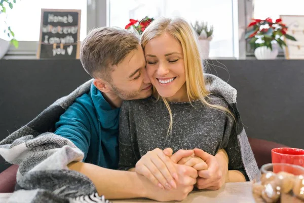 Beijar jovem casal sentado no café juntos sob cobertor — Fotografia de Stock