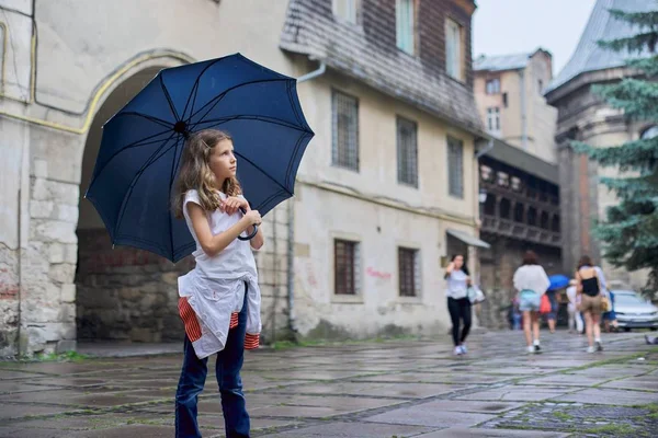 Klein meisje kind in de regen met een paraplu, toeristische oude stad achtergrond — Stockfoto