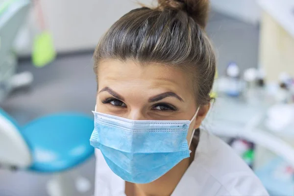 Closeup portrait of smiling female dentist doctor in protective medical mask — Stock Photo, Image