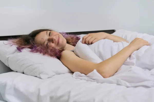 Adolescente chica despertando por la mañana acostado en la almohada en la cama —  Fotos de Stock