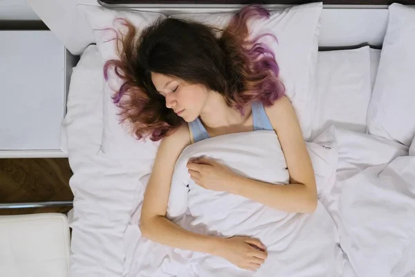 Teen girl sleeping at home in bed, view from above
