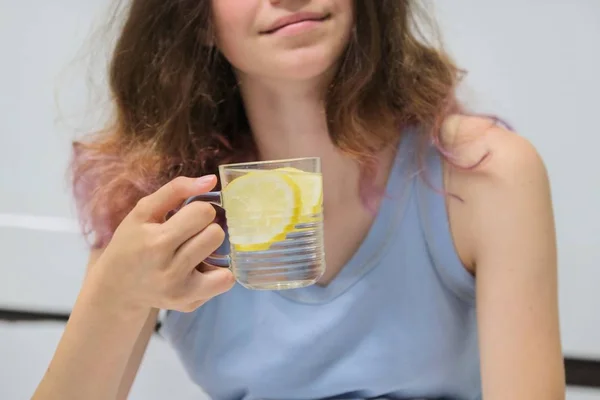 Дівчина сидить у ліжку зі склянкою води з лимоном — стокове фото