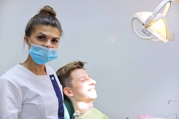 Teen boy on visit to the dentist sitting in chair, young woman doctor treating teeth — Stock Photo, Image