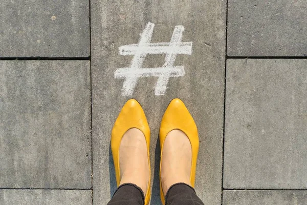 Symbol hashtag na šedém chodníku se ženskými nohami, pohled shora — Stock fotografie