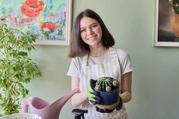 Девочка-подросток держит кактус в горшочке. Хобби и досуг, домашнее садоводство, уход за домом — стоковое фото
