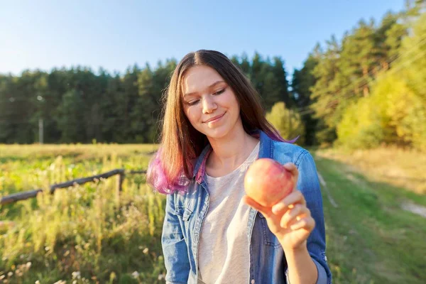 Krásná dospívající dívka s červeným jablkem, šťastná mladá žena na přírodě — Stock fotografie