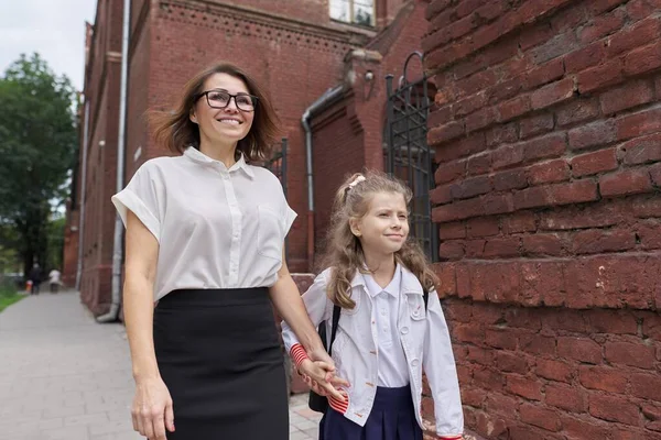 Basisschool schoolmeisje lopen met mam hand in hand — Stockfoto