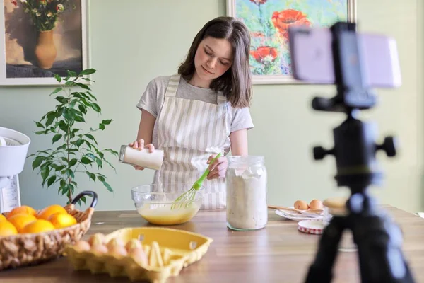 Girl teenager food blogger cooking orange pancakes at home in kitchen