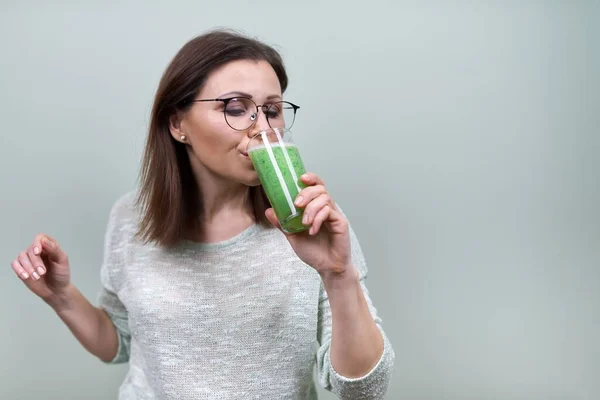 Зрелая женщина с зеленым овощным коктейлем, здоровая веганская диета, женщина пьет сок — стоковое фото