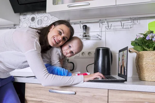 Молодая мать с малышом на руках разговаривает онлайн с психологом — стоковое фото