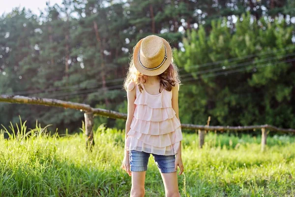 Ragazza felice che si gode le vacanze estive, bambino nella natura sul prato verde che gioca con il cappello — Foto Stock