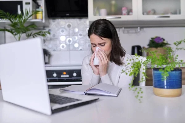 Uma jovem doente. Espirros e tosse com lenço, sentado com laptop — Fotografia de Stock