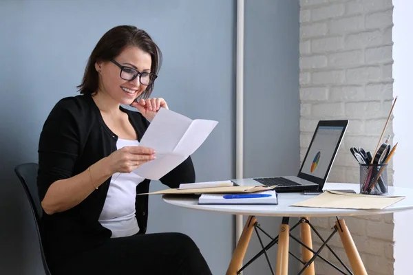 Dojrzała kobieta pracuje w biurze domowym, kobieta siedzi przy biurku z laptopem — Zdjęcie stockowe