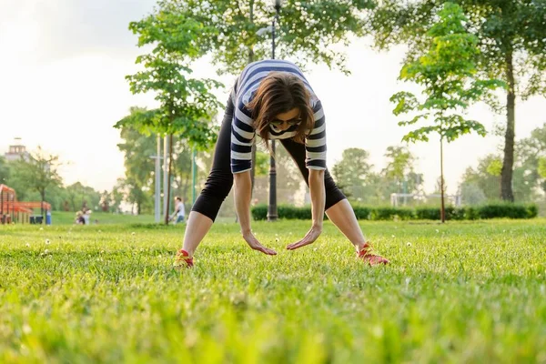 Mature woman doing fitness exercises in park — Stock Photo, Image