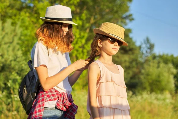 Léto, happy kids walking enjoying nature holiday, older sister braids her younger hair — Stock fotografie