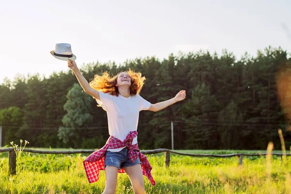 Glad tonårstjej som hoppar med hatt. Glädje av semester sommar natur — Stockfoto