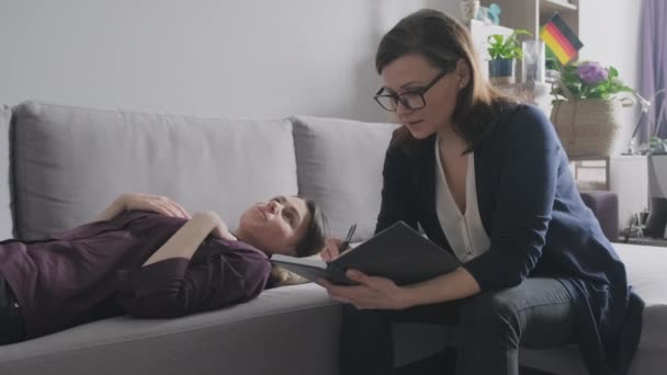 Jeune femme en consultation avec un psychologue. Patiente couchée sur le canapé parlant de problèmes mentaux, traumatisme . — Video